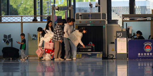 Travelers going through a security screening checkpoint at an airport terminal