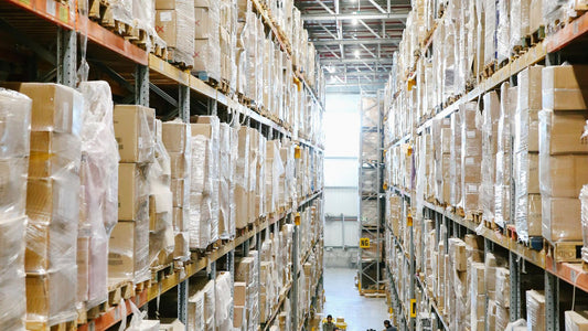 Warehouse aisle stacked with cardboard boxes on industrial shelving, representing bulk wholesale backpack inventory