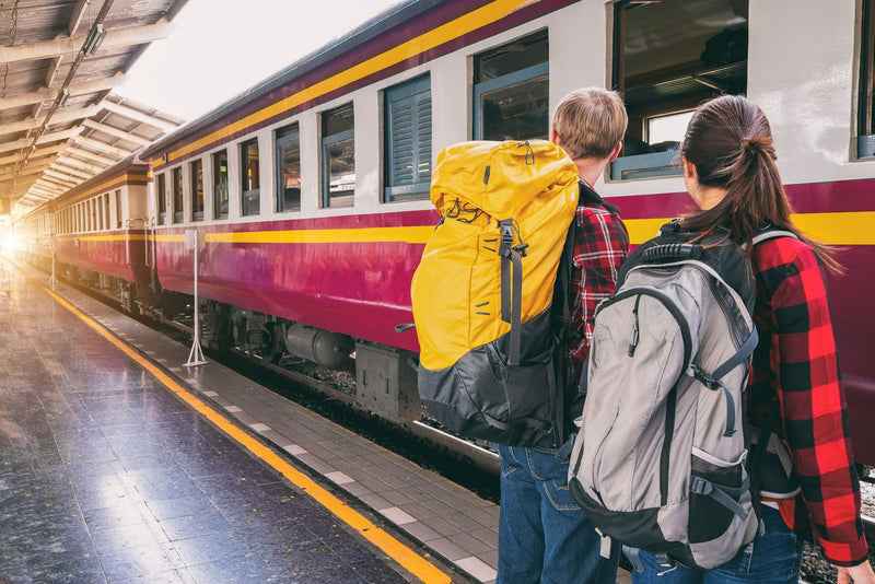 Two backpackers waiting on a train station platform with travel backpacks