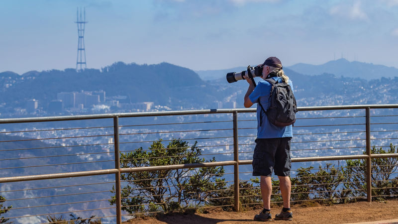 Solo traveler with a backpack photographing a city skyline from a viewpoint