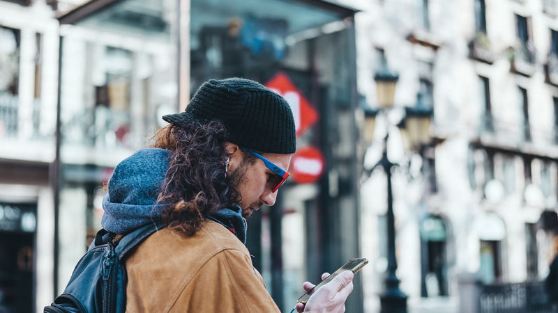 Man with a backpack checking his phone on an urban street