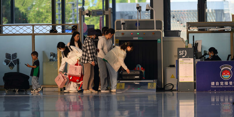 Travelers going through a security screening checkpoint at an airport terminal