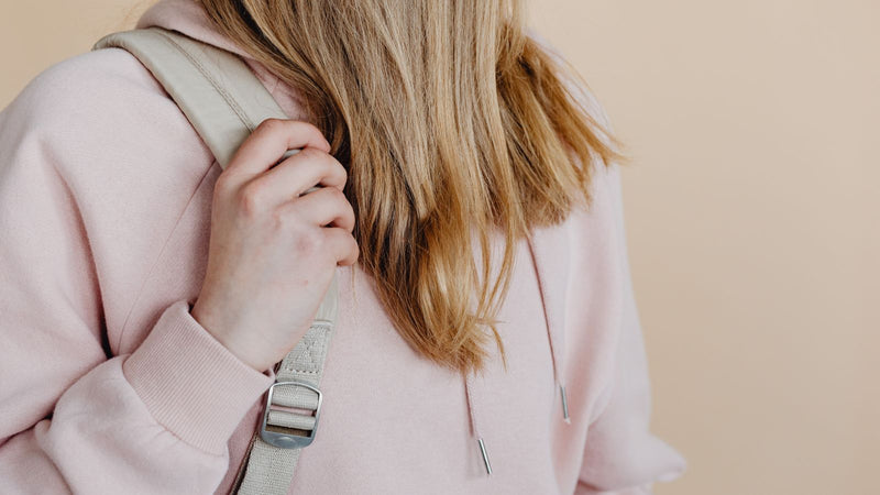 Hand adjusting a backpack shoulder strap
