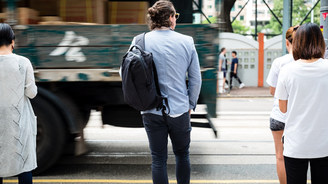 Professional in a suit carrying a backpack while waiting on a city street