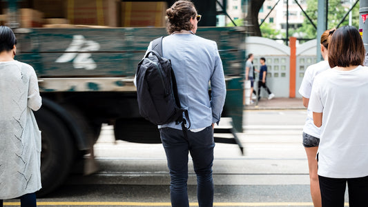 Professional in a suit carrying a backpack while waiting on a city street