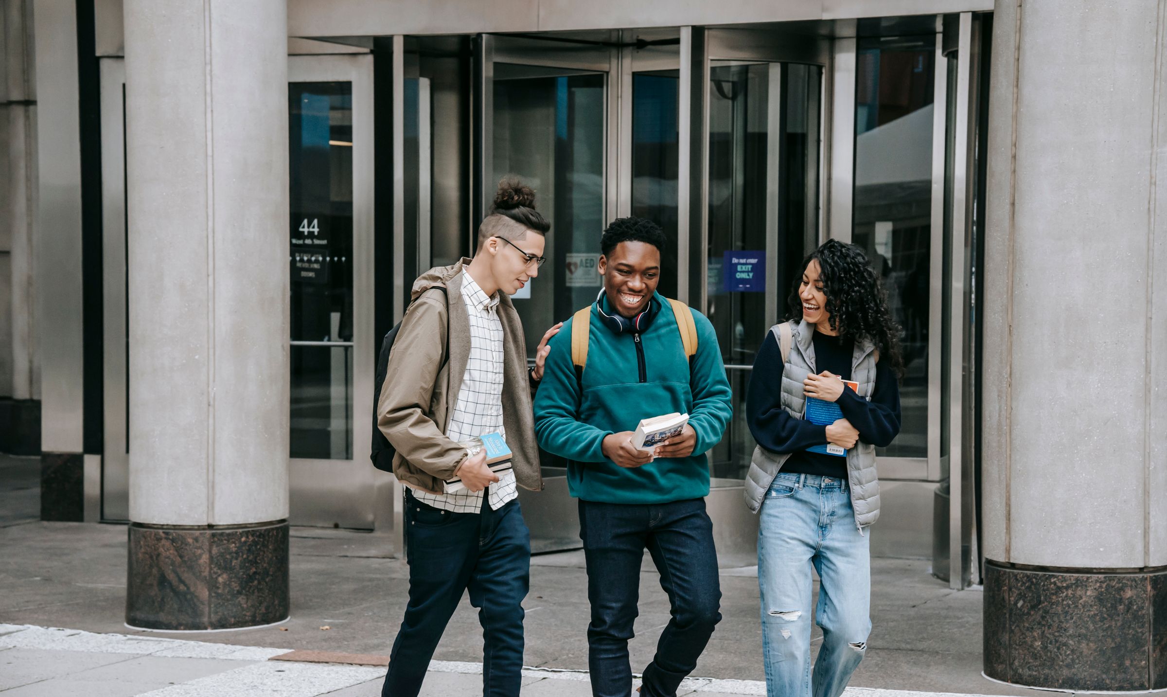 Multiethnic students walking to campus with books and backpacks